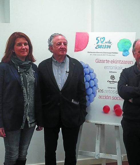 Representantes de Cáritas junto al cartel del congreso.