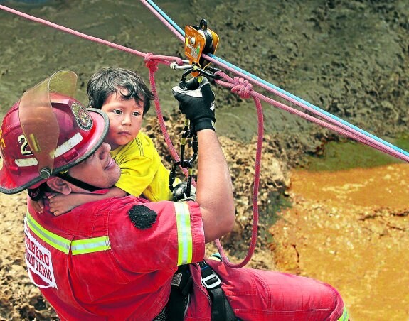 Salvamento. Un bombero rescata a un niño en la localidad de Huachipa, al este de Lima.