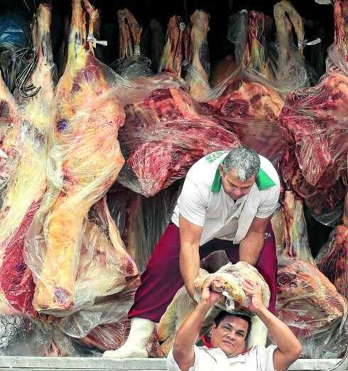 Carne en mal estado. Dos trabajadores se pasan una pieza de carne mientras descargan un camión en Sao Paulo.
