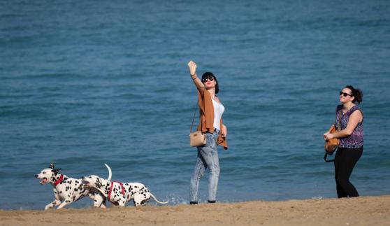 Una mujer se autorretrata con su móvil en la playa de San Sebastián.