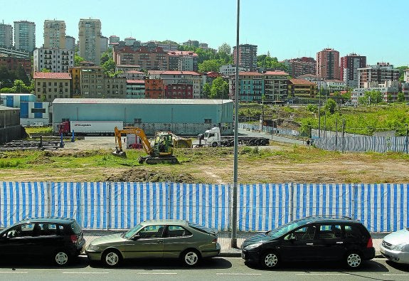 Una excavadora trabaja sobre una parcela vallada en el distrito de Trintxerpe que será conectada a través de una pasarela peatonal y ciclista con Herrera.