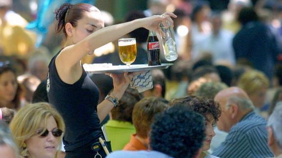 Una camarera sirve bebidas en una terraza. 