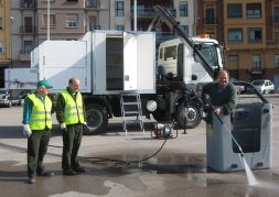 Dos operarios miran al concejal cómo prueba el instrumental del vehículo.