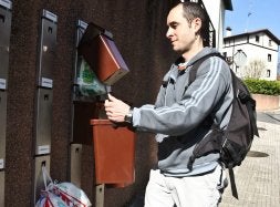 Un joven deposita su cubo en el enganche que por asignación le corresponde.