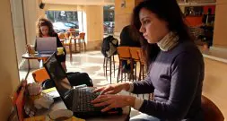 Unas jóvenes navegan por internet en su ordenador portátil en una zona wi-fi.