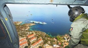 Un helicóptero sobrevuela, ayer, el barco. A la izquierda, el párroco. ::
REUTERS