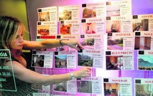 Una empleada coloca anuncios de ventas de pisos en el escaparate de una inmobiliaria de San Sebastián. ::                             J. M. LÓPEZ