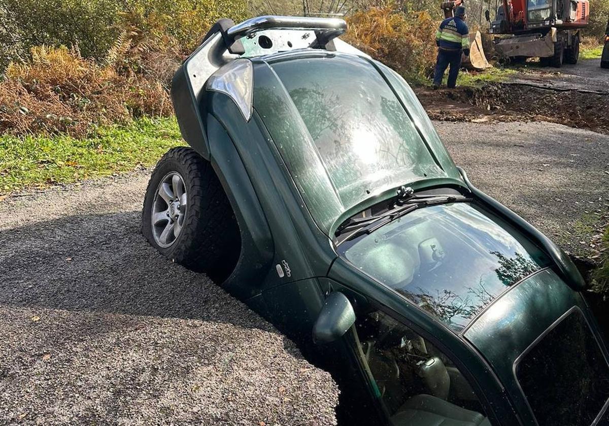 Imagen de uno de los coches que se tragó uno de los socavones abiertos en la carretera LE-4113 que une La Faba con La Cernada.