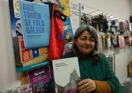 La propietaria de la librería 'El Castillo de Lulavai' de Ponferrada, Julia López, muestra un ejemplar del Diccionario do Galego do Bierzo junto al cartel de la campaña 'Aquí también se fala galego'.