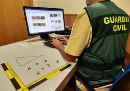 Agente de la Guardia Civil junto a las joyas intervenidas en la operación.