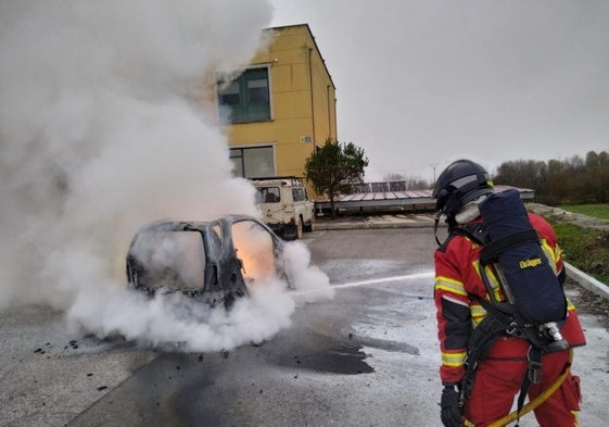 Un bombero apaga el incendio en el vehículo aparcado en el parking de un hostal en Cubillos del Sil.