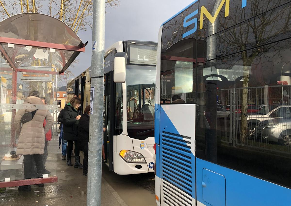 Imagen secundaria 1 - De arriba abajo: una mujer se informa de los horarios del autobús; usuarios subiendo al transporte público y uno de los paneles de la parada del hospital.