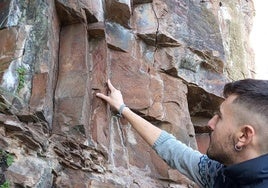 El concejal de Turismo de Vega de Espinareda, Pablo Taladrid, muestra los daños ocasionados en las pinturas rupestres de Sésamo, en una imagen de archivo.