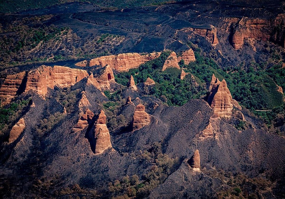 Imagen aérea de los picachos rojizos de Las Médulas en medio de la destrucción causada por el fuego.