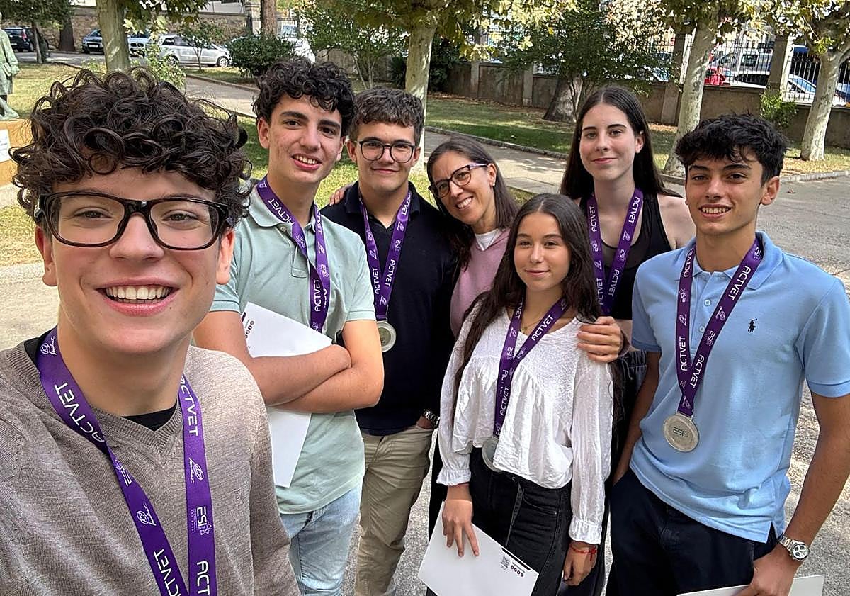 Imagen principal - La profesora berciana en dos imágenes con sus alumnos y montrando la medalla con la inscripción '¡Viva Ponferrada!' que le regalaron.