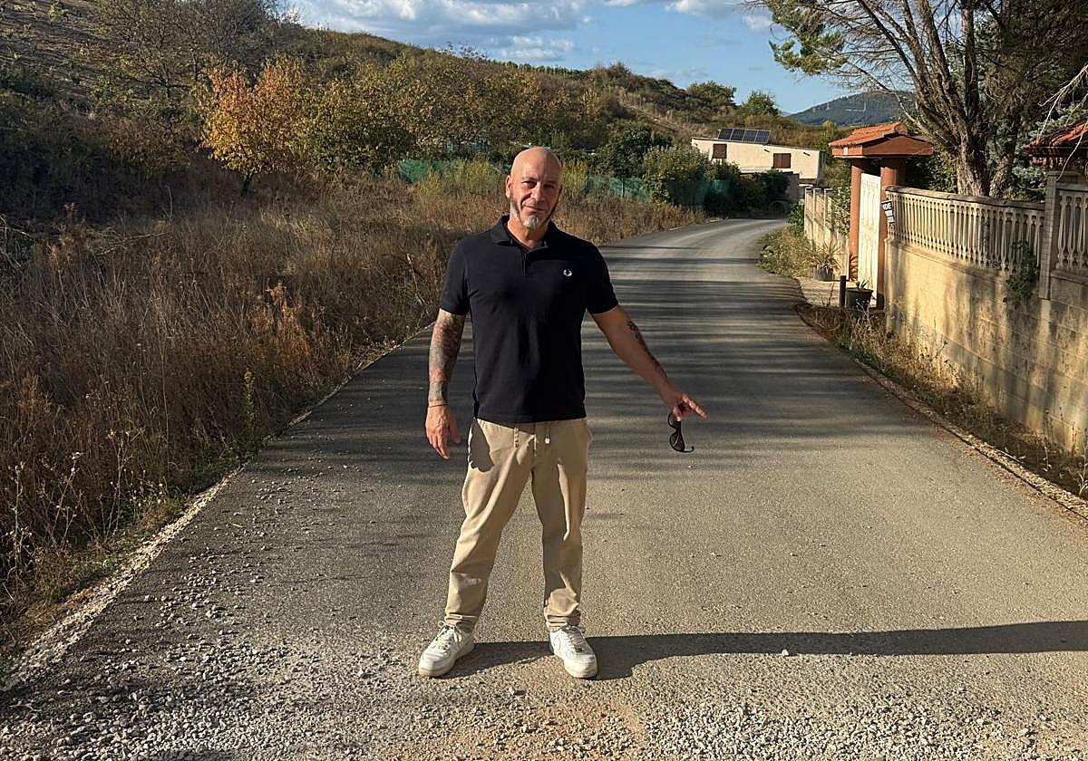 Luciano Arias, presidente de la asociación vecinal Camino del Escaril, señalando el tramo donde acaba el asfaltado y comienza otra vez el camino de tierra.