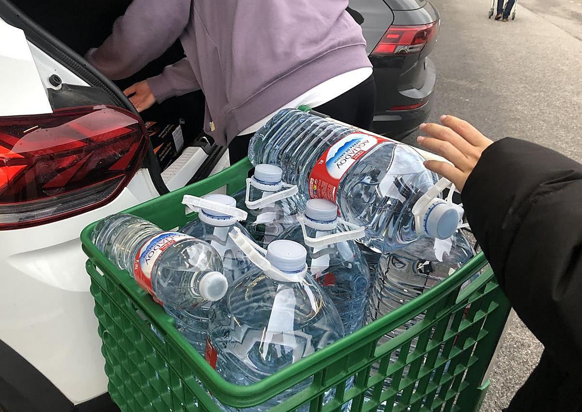 Imagen secundaria 1 - Dos de los puntos de abastecimiento de agua en la avenida de Montearenas (foto superior) y junto al Burger King (foto inferior), y garrafas de agua en el carro de un supermercado (centro).