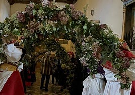Imagen de las mujeres de la cofradía en Matachana sujetando los arcos de hiedra en la celebración de la tradición.