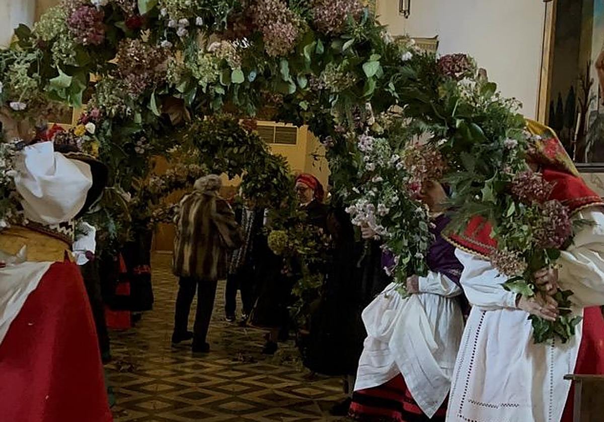 Imagen de las mujeres de la cofradía en Matachana sujetando los arcos de hiedra en la celebración de la tradición.