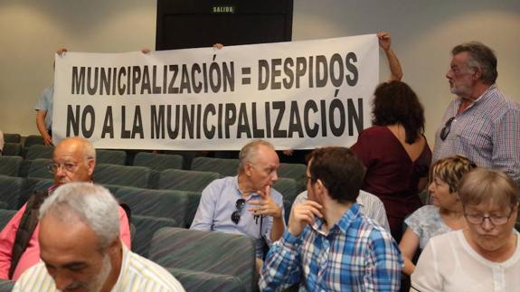 Varios trabajadores del Transporte Urbano de Ponferrada, TUP, despliegan una pancarta contra la municipalización del servicio, durante el pleno.