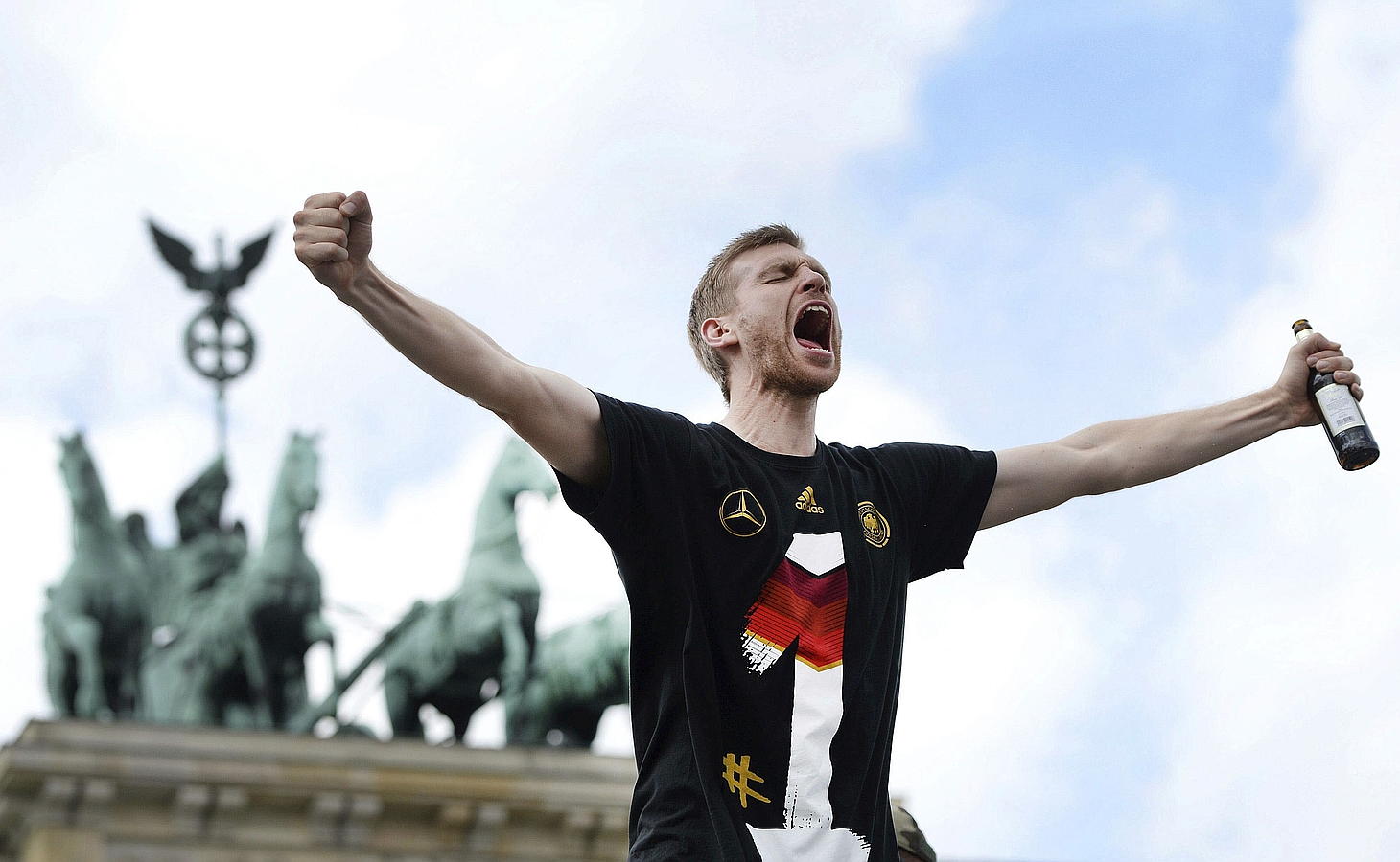 LA SELECCIÓN ALEMANA CELEBRA LA COPA DEL MUNDO CON MILES DE AFICIONADOS. El alemán Per Mertesacker celebran la Copa del Mundo con los cientos de miles de aficionados que recibieron al combinado alemán en la Puerta de Brandeburgo en Berlín.