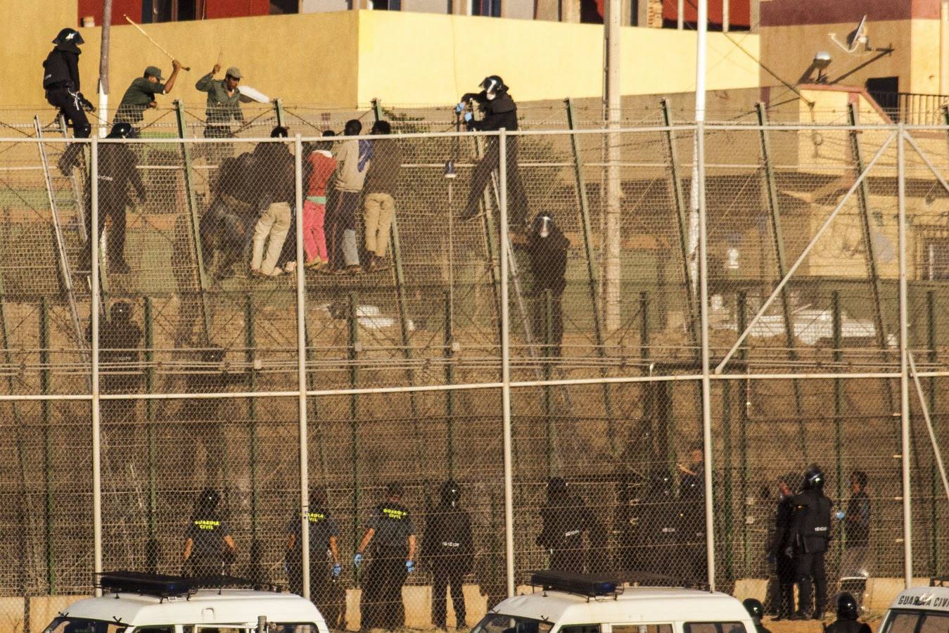 A golpes en la frontera.. Soldados marroquíes a golpes con los inmigrantes. Al otro lado, las fuerzas de seguridad españolas.