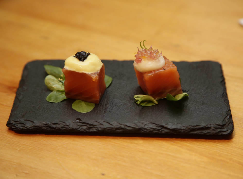 Dados de salmón en dos gustos (El Abezu). Dados de salmón marinado, uno con espima de alioli de mango y ajo negro y, el otro, con caviar de cítrico y esfera de yogur.
