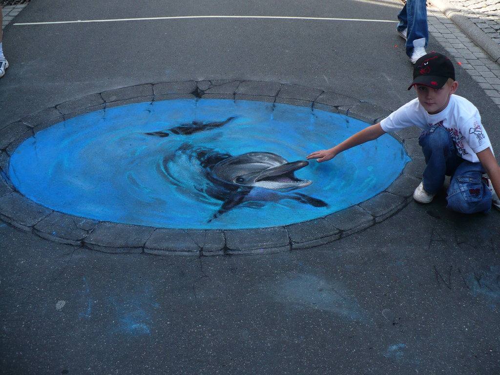 Un delfín en la ciudad. Este niño intenta tocar lo que en realidad es un dibujo en el suelo.