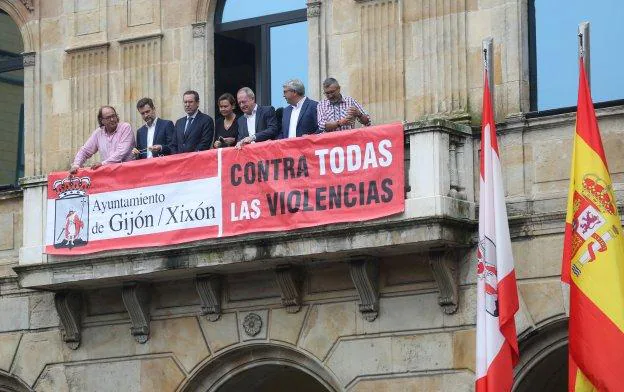 La alcaldesa y los portavoces de los grupos municipales despliegan la pancarta contra la violencia en el balcón del Ayuntamiento. 