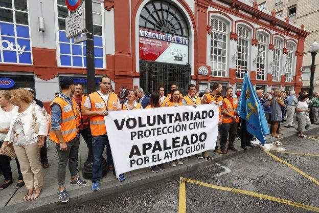 El grupo de voluntarios, ayer, con una pancarta de protesta, ante el Mercado del Sur. 