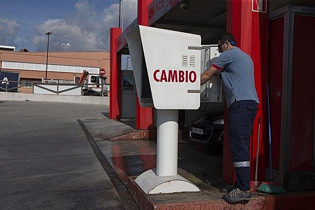 Un empleado de la gasolinera de la avenida de Roces revisa la máquina violentada la madrugada de ayer. 