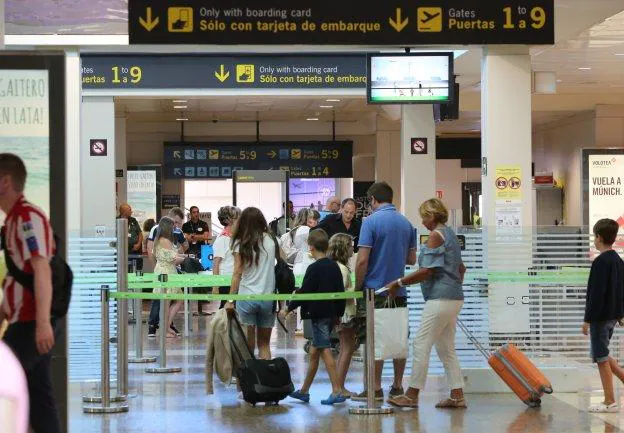 Un grupo de pasajeros pasa por el control de seguridad del aeropuerto de Asturias con un solo arco abierto . 