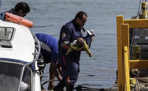 Un bombero carga el cuerpo sin vida de un bebé en uno de los naufragios. 