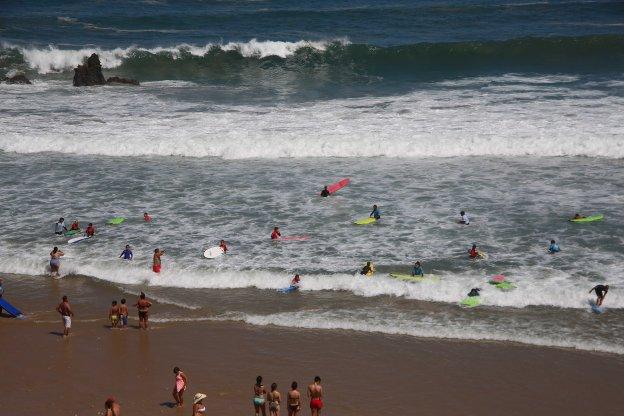 Un grupo de alumnos y profesores practica surf en la playa llanisca de San Antolín. 