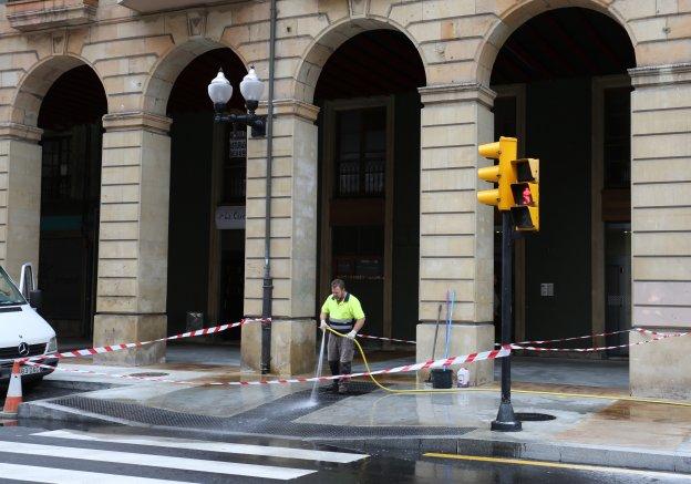 Arriba, un operario limpia las baldosas de un paso peatonal. Abajo, otro rellena la junta de dilatación del pavimento de hormigón. 