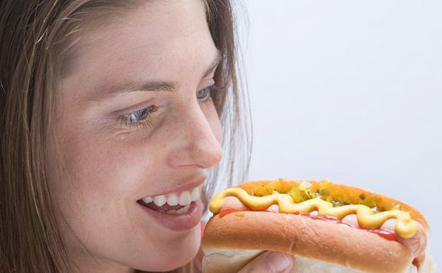 Una mujer, comiendo un perrito caliente.