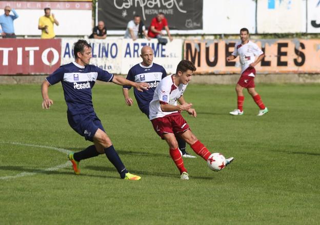 El fabril Iván Suárez golpea el balón frente a Saavedra, con Óscar Pérez detrás. 