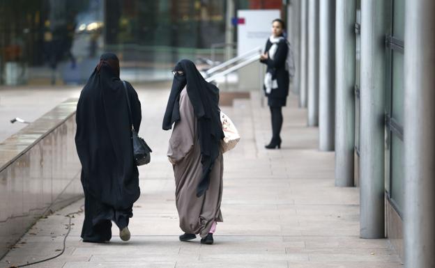 Dos mujeres, llevando un burka.