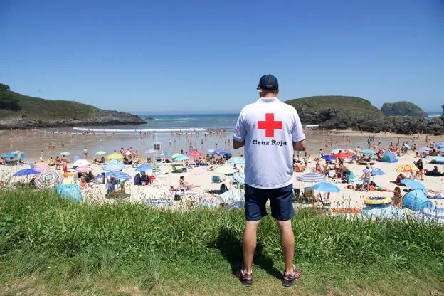 Un miembro del servicio de salvamento en playas de Llanes, que gestiona Cruz Roja, vigila el arenal de Barro. 
