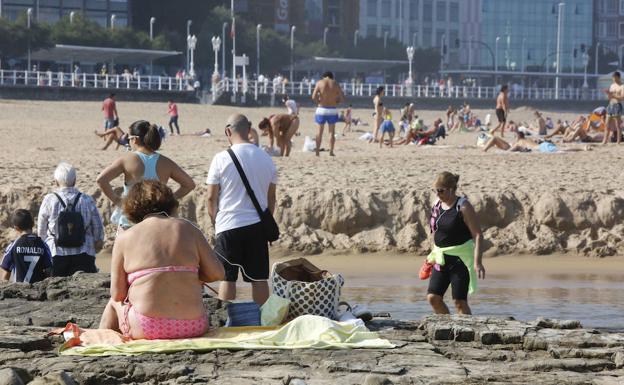 Numerosos gijoneses han aprovechado la mañana de sol para disfrutar de la playa.