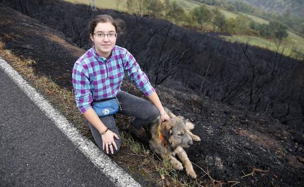 Leticia Fernández, junto a ‘Turco’, en la zona de Valledor, arrasada por las llamas. 