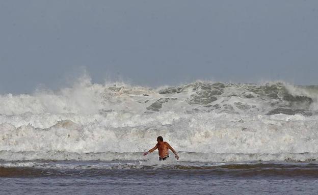 Un bañista sale del agua en la playa gijonesa de San Lorenzo.