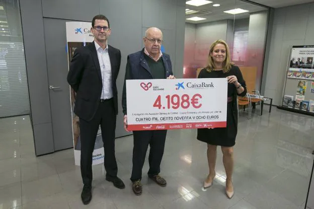 Nieves Vigón, directora de área de negocio de Caixabank en Gijón, entrega el cheque con los 4.198 euros recaudados en la marcha familiar del pasado fin de semana a Juan García Adaro, vicesecretario de la Cocina Económica, en presencia de Goyo Ezama, director general de EL COMERCIO. 