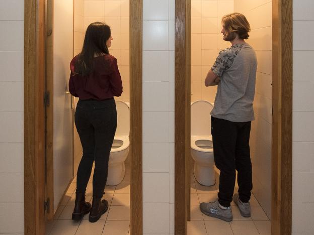 Cristina Díaz y Diego Castañón, estudiantes de la Facultad de Psicología, posan en los baños unisex del centro. 