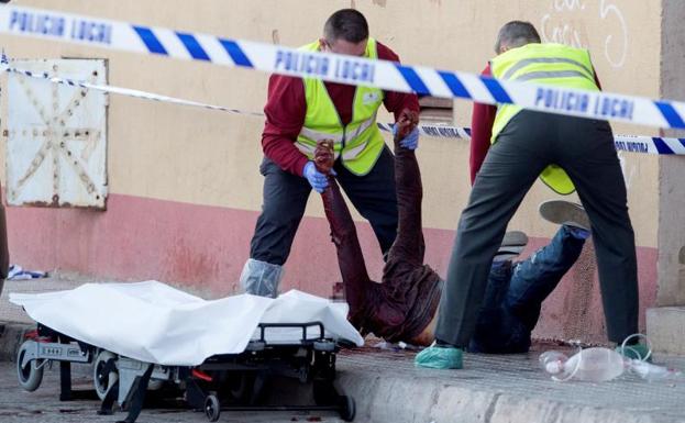 Efectivos policiales retiran el cadáver de uno de los dos hombres que murieron ayer.