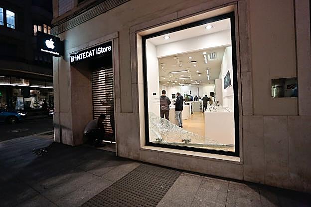 Operarios reemplazan la persiana metálica de la tienda de Apple que fue reventada durante el asalto. 