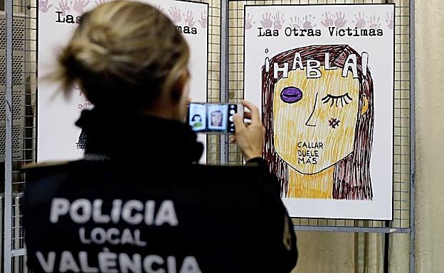 Una policía fotografía un cartel contra la violencia machista.