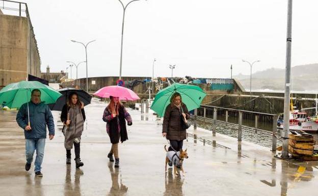 Turistas paseando bajo la lluvia en Llanes.