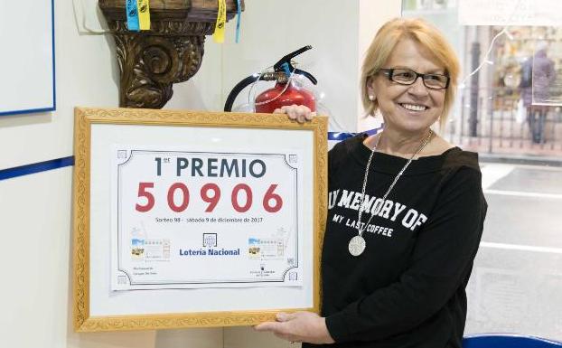 Eva Ordóñez posa con el cartel que anuncia el primer premio de la Lotería Nacional junto a la imagen de la Santina. 