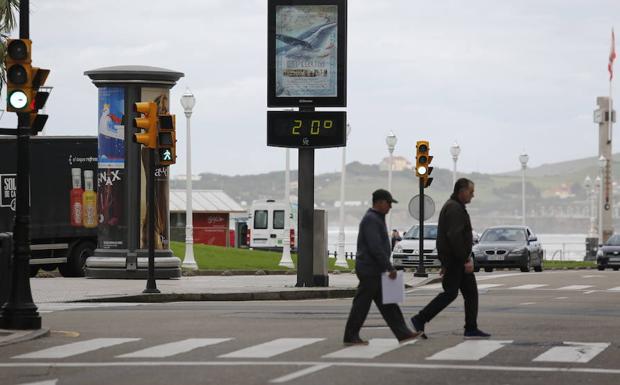 Imagen. Dos gijoneses, ante un termómetro que marca veinte grados de temperatura. 